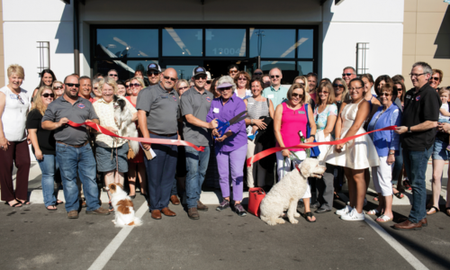 The grand opening of Pet Central with entire staff and their pets cutting the ribbon